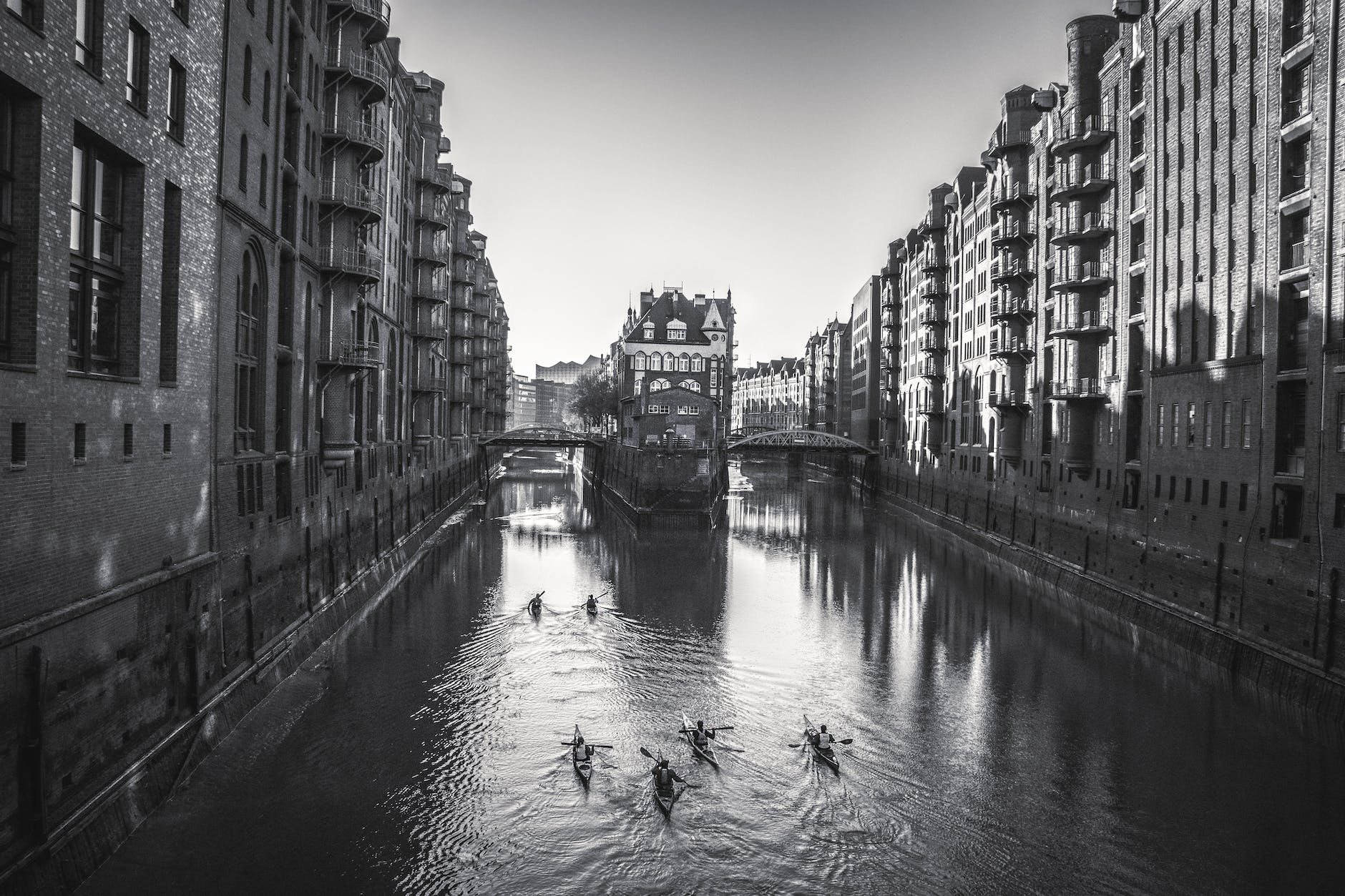 people kayaking on a river between buildings